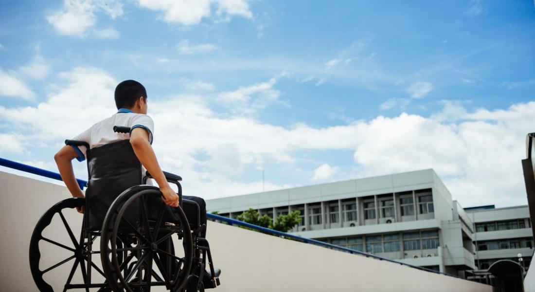 Chico en silla de ruedas en frente de un edificio